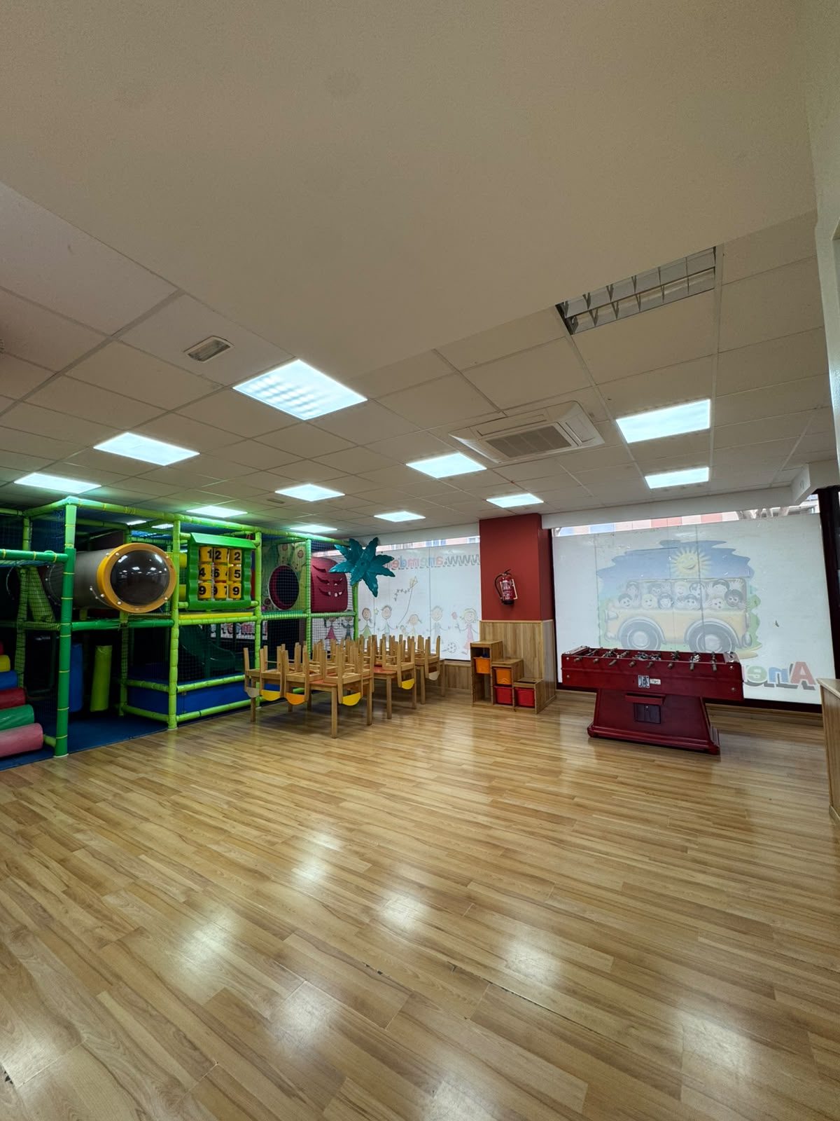 Sala principal amb el parc de boles, taules i cadires i el futbolí al fons